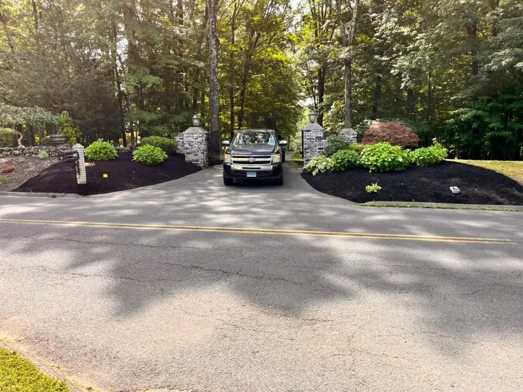 Wide residential driveway entrance finished with dark mulch and plantings