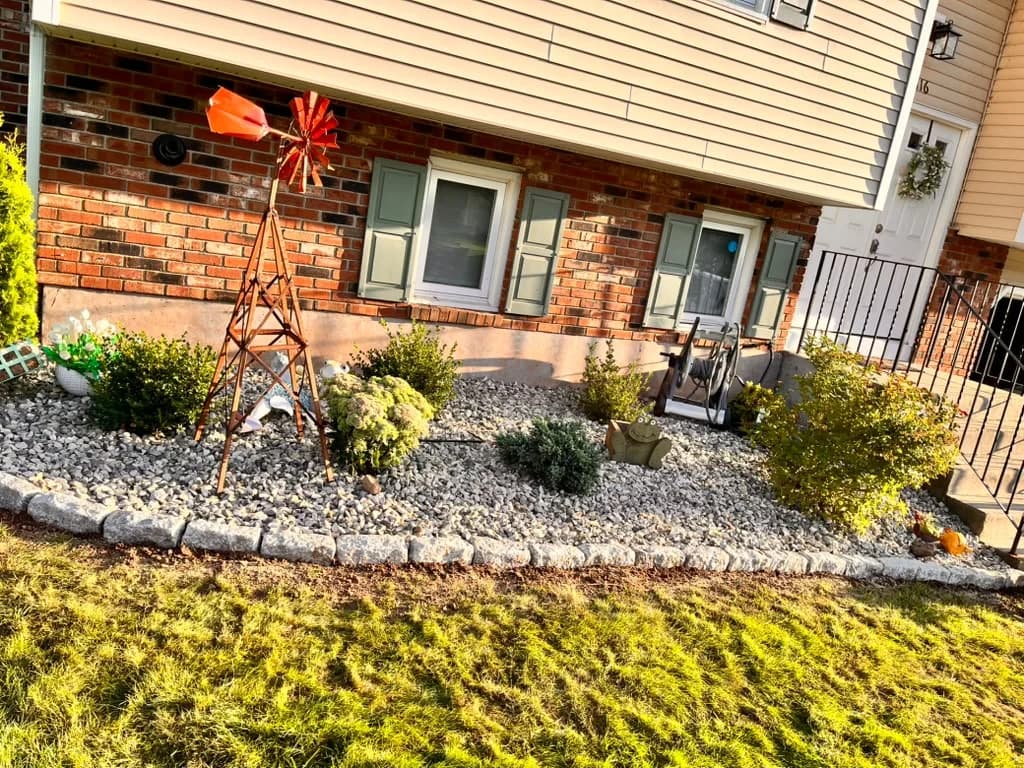 Foundation garden finished with decorative stone, plantings, and a block edge