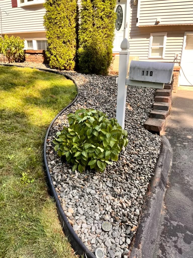 Mailbox landscape bed finished with decorative stone and a curved border